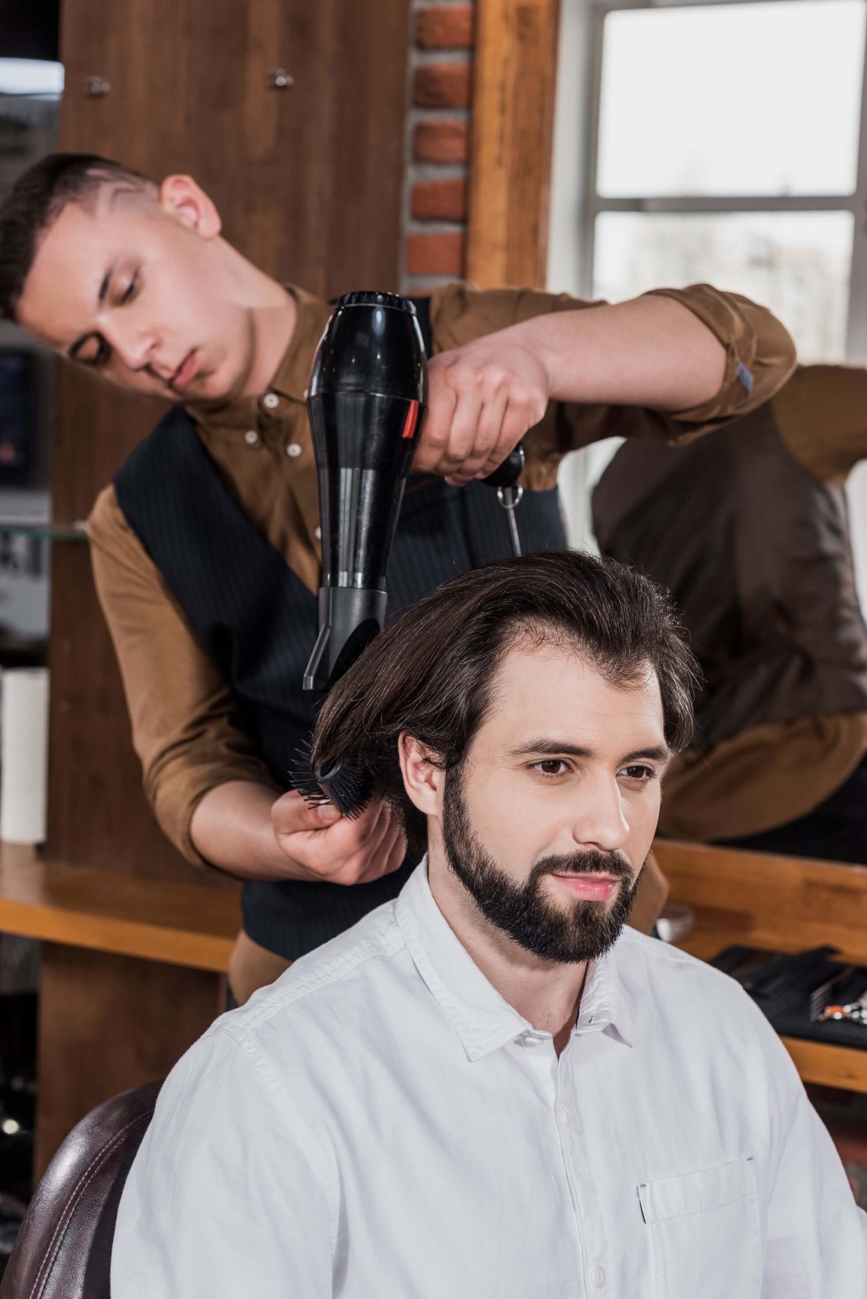 serious-barber-combing-hair-of-customer-with-haird-K3HGKNC.jpg